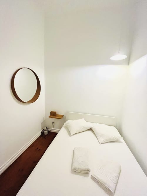 Minimalist bedroom at Royal Prince Garden Apartments, Lisbon, with white bed, wooden mirror, recessed lighting, and parquet