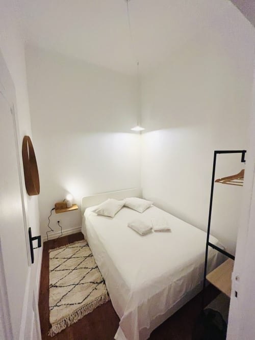 Minimal bedroom with white bed, pendant light, wooden decor, and patterned rug at Royal Prince Garden Apartments, Lisboa
