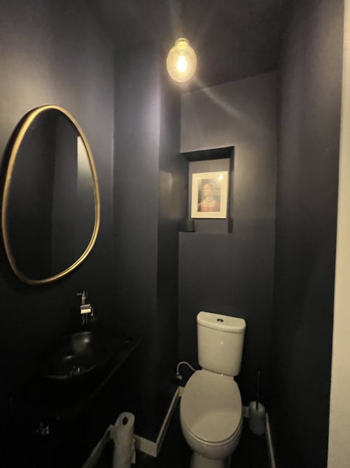 Modern black bathroom at Royal Prince Garden Apartments, Lisbon, featuring round mirror, white toilet, and ambient lighting