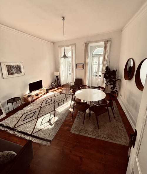 Sala de estar moderna e luminosa com mesa de jantar, escrivaninha, piso de madeira e portas francesas com vista para jardins