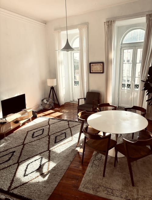 Bright modern living room at Royal Prince Garden Apartments in Lisbon with dining table, seating, TV, and large windows