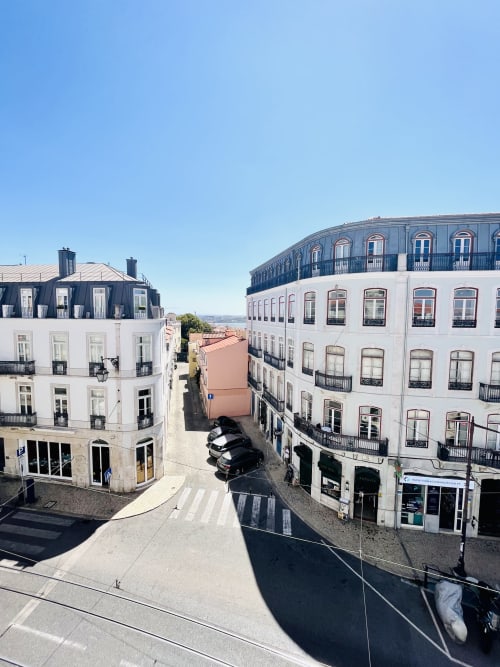 Lisbon street view showing white Haussmann-style buildings with mansard roofs and wrought iron balconies near Royal Prince
