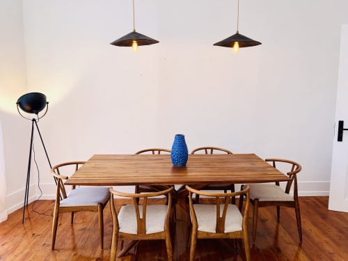 Modern dining room in Lisbon apartment with wooden table, mid-century chairs, pendant lights, and blue vase centerpiece
