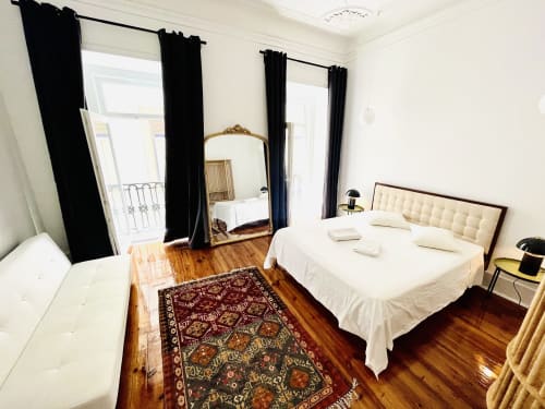 Elegant bedroom at Royal Prince Garden Apartments in Lisbon with wooden floors, canopy bed, and black curtains