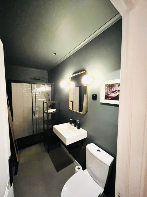 Modern bathroom at Royal Prince Garden Apartments in Lisboa with dark walls, white sink, toilet, and gold-framed mirror with
