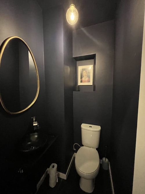 Modern bathroom in Royal Prince Garden Apartments, Lisboa, featuring dark walls, round gold-framed mirror, white toilet, and