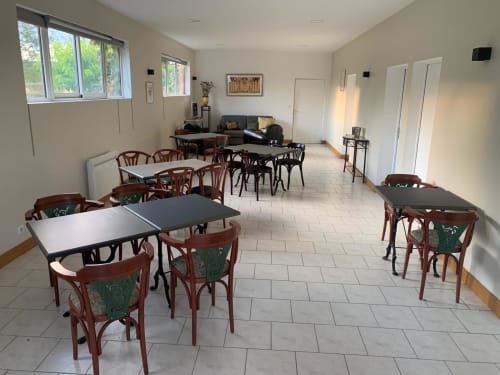 Hall de réception de l'hôtel Accolade à Châteaudun avec tables de restaurant, chaises en bois et vue sur le jardin