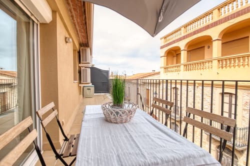 Balcón soleado en Finques Garcia Enrich en Palafrugell con sillas de madera, plantas en maceta y arquitectura amarilla