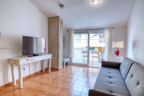 Salón moderno con terraza en Finques Garcia Enrich, Palafrugell. Televisión de pantalla plana, sofá gris y balcón