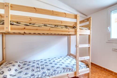Literas de madera con colchones azules estampados en un dormitorio luminoso de Finques Garcia Enrich, Palafrugell