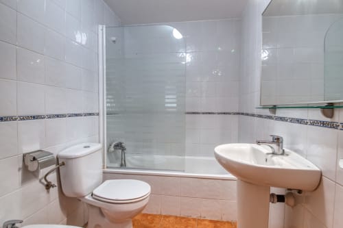 Baño moderno con ducha de cristal, azulejos blancos y lavabo tipo pedestal en el hotel Finques Garcia Enrich de Palafrugell