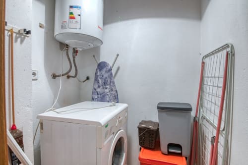 Lavadero compacto en el hotel Finques Garcia Enrich de Palafrugell con lavadora, calentador de agua y almacenamiento.