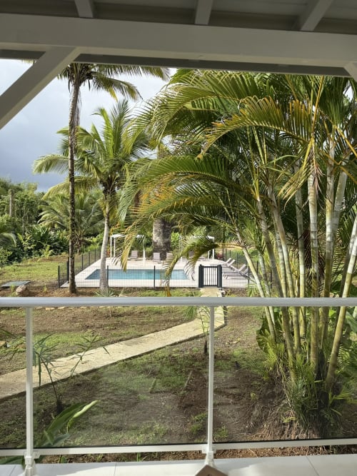Vue depuis le bungalow Ixora du Domaine de la Glacière, Guadeloupe, avec piscine et palmiers