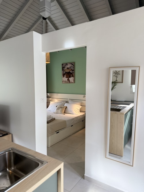 Bungalow Ixora au Domaine de la Glacière à Petit-Bourg - chambre moderne avec mur d'accent vert et coin cuisine