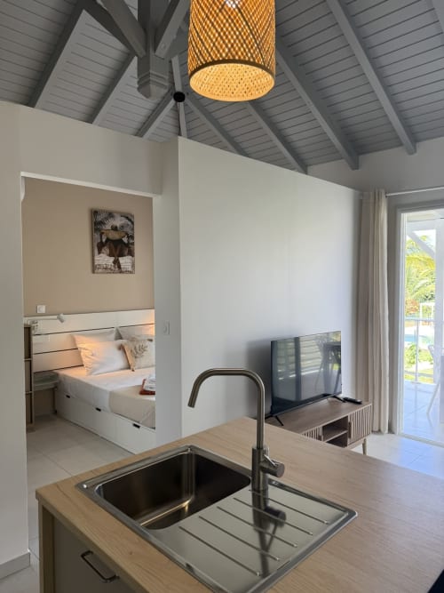 Kitchenette du bungalow Hibiscus à Domaine de la Glacière avec évier moderne, plafond voûté et vue sur la chambre