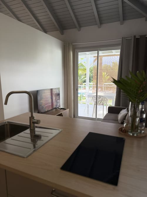 Kitchenette du bungalow Hibiscus à la Domaine de la Glacière, vue sur piscine, évier moderne et portes-fenêtres