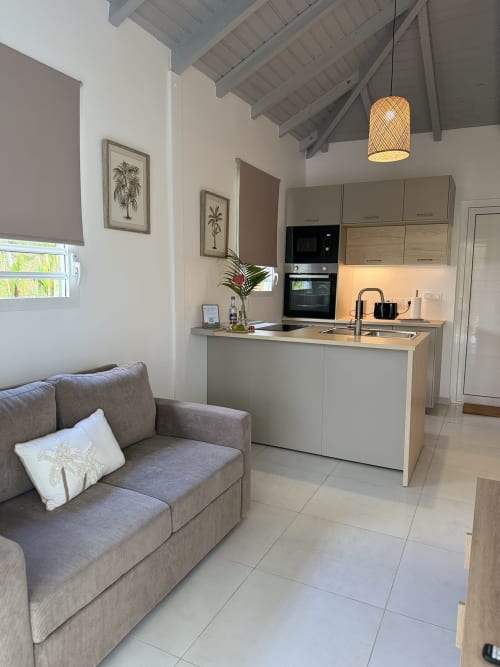 Cuisine et séjour du bungalow Hibiscus au Domaine de la Glacière, Petit Bourg avec équipements modernes et vue sur la piscine