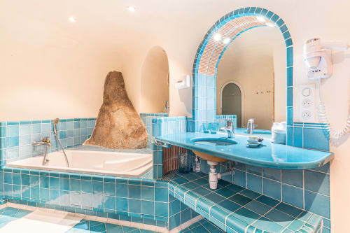 Salle de bain aux carreaux turquoise, grand miroir arqué et élément en pierre unique à la Villa Marina Di Cavu, Bonifacio