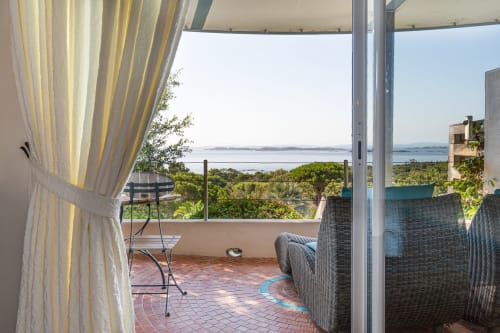 Terrasse avec vue sur mer à la Villa Marina Di Cavu à Bonifacio, France, avec mobilier en rotin et rideaux jaunes
