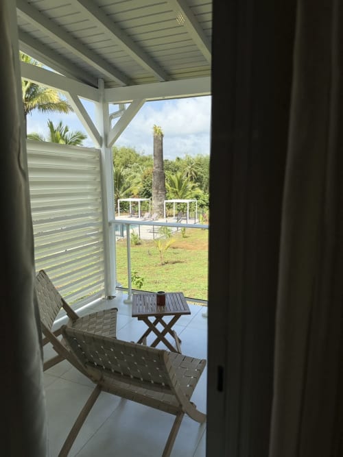 Balcon du bungalow Tiaré à Domaine de la Glacière avec chaises longues, vue sur la piscine et jardins tropicaux à Petit Bourg