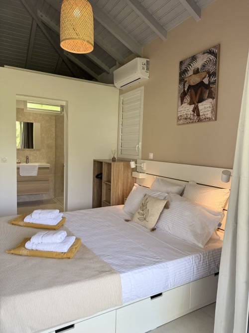 Chambre du bungalow Tiaré au Domaine de la Glacière, Petit Bourg avec salle de bains attenante, suspension tissée et design moderne