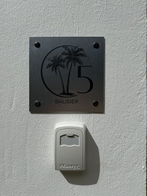 Pancarte numéro 5 Balisier avec motif de palmier et boîte à clés Master Lock sur mur blanc à Domaine de la Glacière