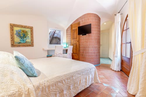 Spacieuse chambre double à la Villa Marina Di Cavu à Bonifacio avec literie blanche, voûte en brique, TV, bureau et vue sur le jardin