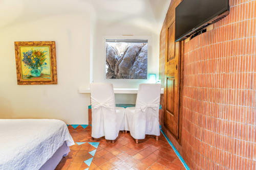 Chambre spacieuse de la Villa Marina Di Cavu à Bonifacio avec lits jumeaux, vue sur le jardin et mur en briques