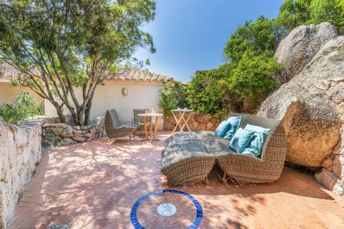 Terrasse isolée avec chaise longue en rotin, rochers et coin ombragé à la Villa Marina Di Cavu, Bonifacio