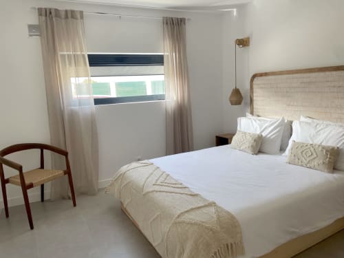 Quarto luminoso da villa Casa Amado em Bordeira com vista ao mar, cabeceira em vime, roupa de cama branca e cortinas translúcidas