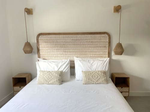 Quarto luminoso na villa Casa Amado com cabeceira de rattan, roupa de cama branca, almofadas bege, mesas de cabeceira de madeira e luminária