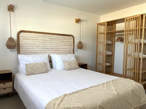 Quarto moderno e iluminado da villa Casa Amado em Bordeira com cabeceira tecida, roupas de cama brancas, móvel de madeira e luminárias pendentes.
