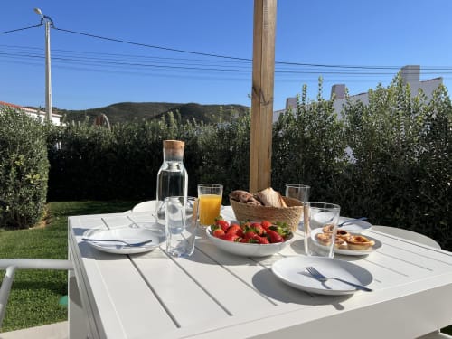 Outdoor dining table at Casa Amado villa in Bordeira with fresh strawberries, bread, orange juice, and water glasses