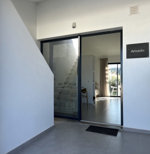Entrada da villa Casa Amado com portas de vidro deslizantes abrindo para espaço de estar moderno com vista para o mar em Bordeira, Portugal