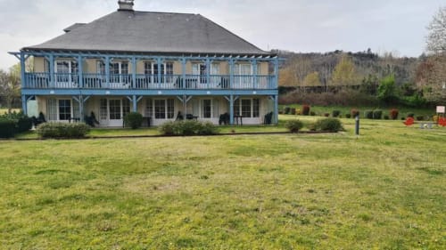 Manoir bleu et blanc avec balcons enveloppants situé dans la campagne de Darazac