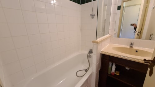 Salle de bain immaculée avec douche carrelée blanche, baignoire et lavabo au studio Conciergerie Pour Tous à Darazac