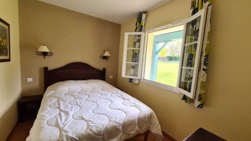 Chambre cosy à la Conciergerie Pour Tous By Patty à Darazac avec lit queen, murs jaunes et vue sur le jardin