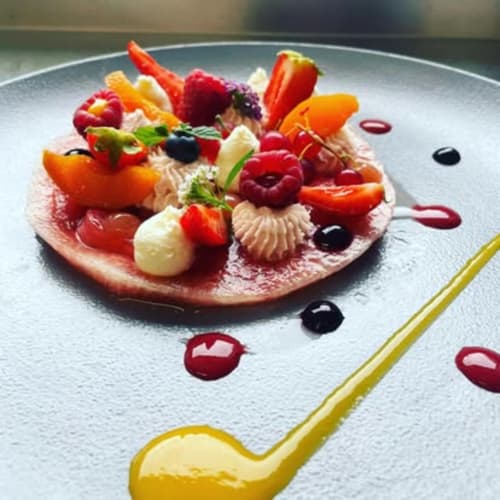 Élégant dessert en assiette garni de baies fraiches, crème et fruits colorés au Domaine du haut de la Dombes