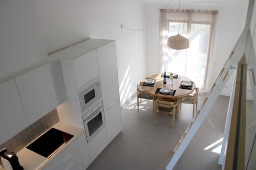 Cozinha moderna branca e área de refeições com mesa de madeira na villa Casa Amoreira em Bordeira, Portugal
