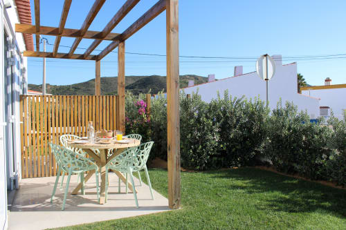 Outdoor dining area at Casa Amoreira villa in Bordeira with wooden pergola, mint chairs, and mountain views