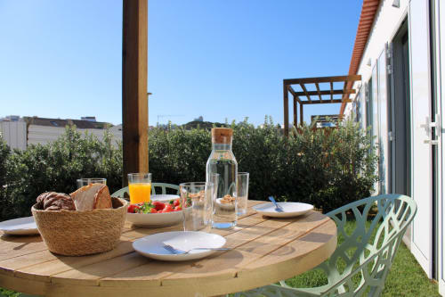 Mesa de refeições ao ar livre na villa Casa Amoreira em Bordeira com pão, frutas frescas, sumo e vista para o mar