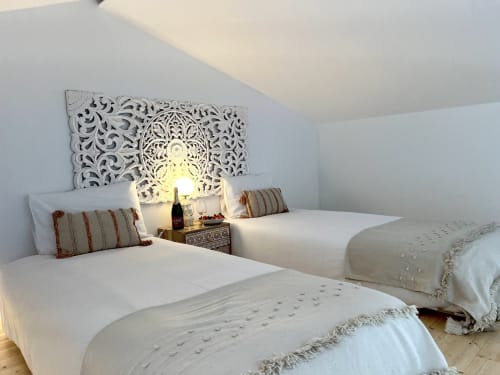 Camas gêmeas com almofadas listradas na villa Casa Amoreira, Bordeira, Portugal, com cabeceira ornamentada e vista para o mar