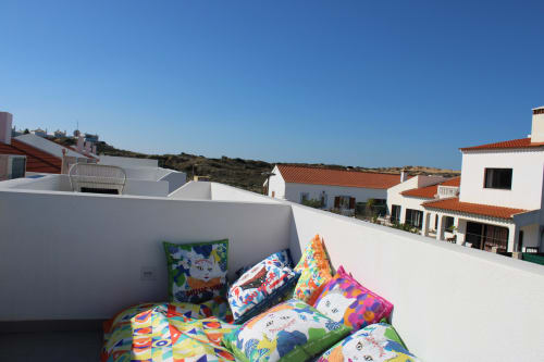 Almofadas coloridas e espreguiçadeiras em um terraço ensolarado da villa Casa Amoreira em Bordeira, Portugal
