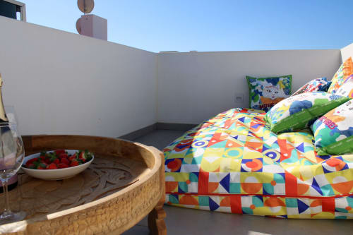 Cama com padrões coloridos e mesa de madeira com morangos frescos no terraço da vila Casa Amoreira em Bordeira