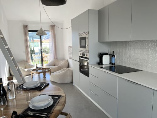 Cozinha moderna e sala de estar na villa Casa Arrifana, Bordeira com vistas para o mar, armários brancos e acomodações confortáveis.