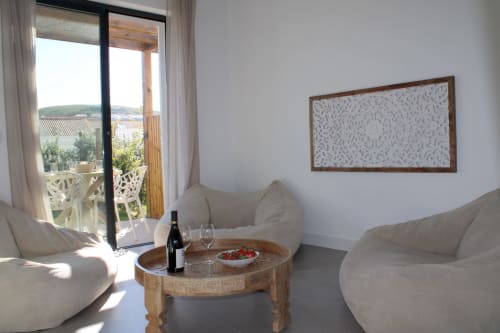 Sala de estar de vila moderna com móveis creme, vista para o mar pela porta da varanda, mesa de madeira com vinho e aperitivos, Bordeira