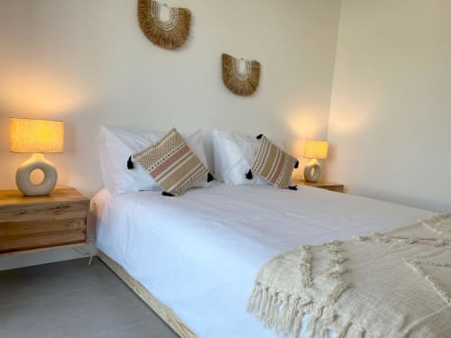 Quarto moderno com roupa de cama branca, almofadas estampadas e iluminação quente na villa Casa Castelejo em Bordeira, Portugal