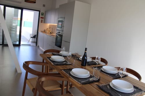 Sala de jantar moderna da villa Casa Castelejo com mesa de madeira, arranjo de mesa e cozinha contemporânea ao fundo