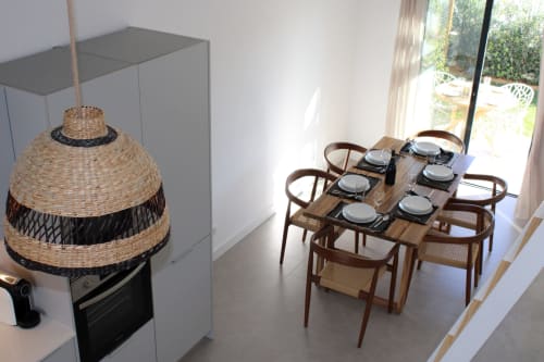 Sala de jantar moderna da villa Casa Castelejo com cadeiras de madeira, mesa posta e luminária de fibra trançada sobre balcão da cozinha