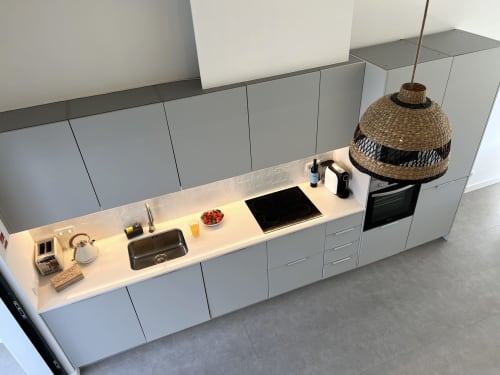 Cozinha moderna da villa Casa Castelejo em Bordeira com armários brancos, fogão preto, pia em aço inoxidável e luminária de palha